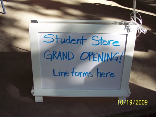white easel with blue text "Student Store Grand Opening!"